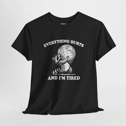 Hanging view of black T-shirt featuring a vintage style sketch of a raccoon carrying the world with the phrase “Everything Hurts and I’m Tired.” The official uniform of burnt out. Part of the Vivid Divergence Memewear Collection!