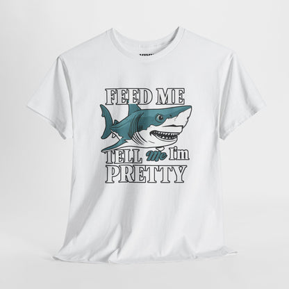 Hanging view of white T-shirt featuring a graphic of an open-mouthed shark with the phrase "Feed Me & Tell Me I’m Pretty" in bold serif font. Aggressively affectionate energy. Part of the Vivid Divergence Memewear Collection!
