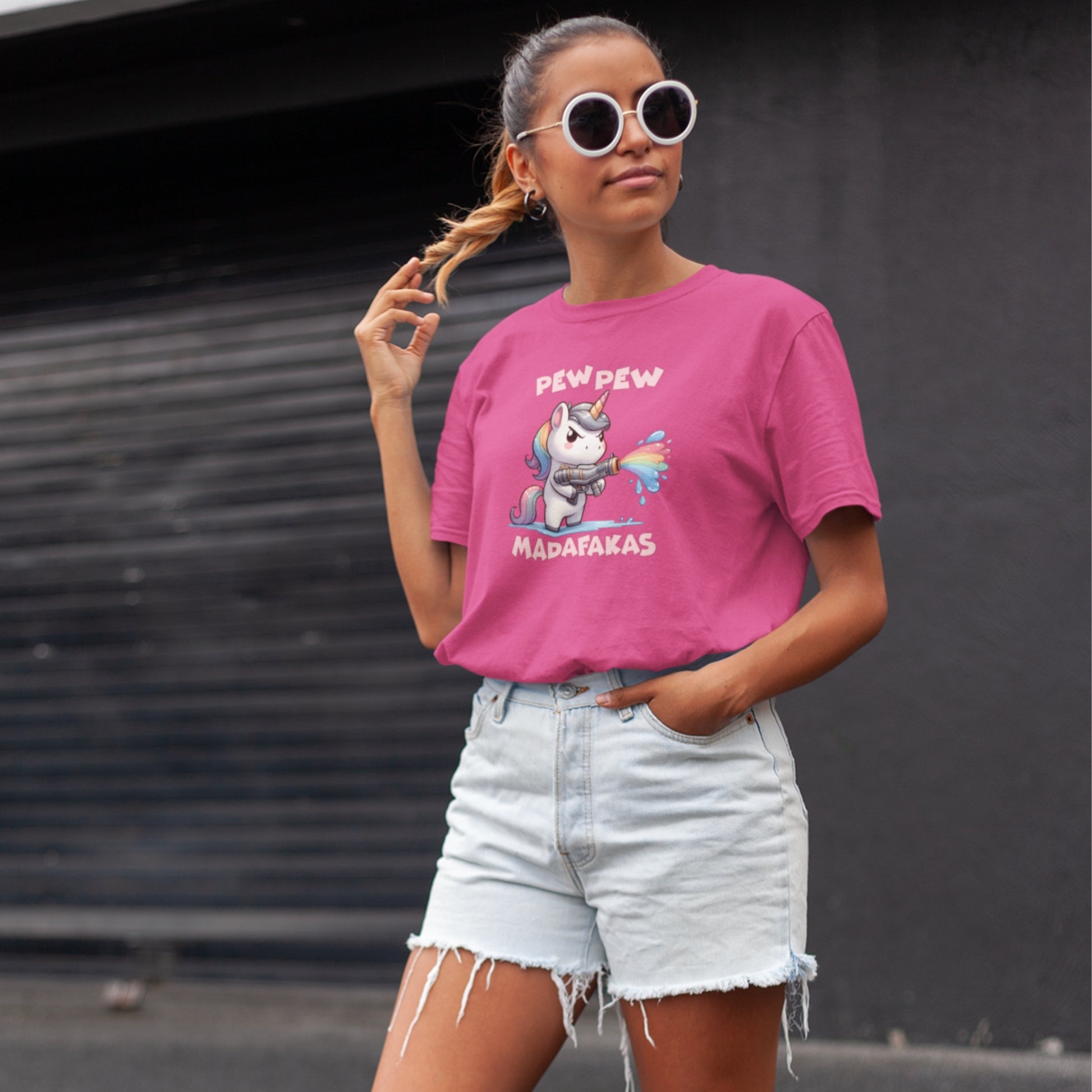 Woman wearing a pink T-shirt with a "Pew Pew Madafakas" unicorn graphic, styled casually. Part of the Vivid Divergence Sensory Friendly Unisex Tees Range.