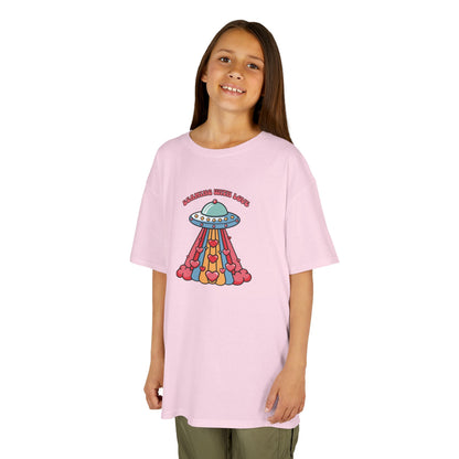 Girl wearing a pink "Beaming With Love" kids T-shirt with a colorful UFO beaming down hearts. Part of the Vivid Divergence Sensory Friendly Kids Shirts Range. The perfect T-shirt for sensory-sensitive kids and comes with a Sensory Satisfaction Promise.