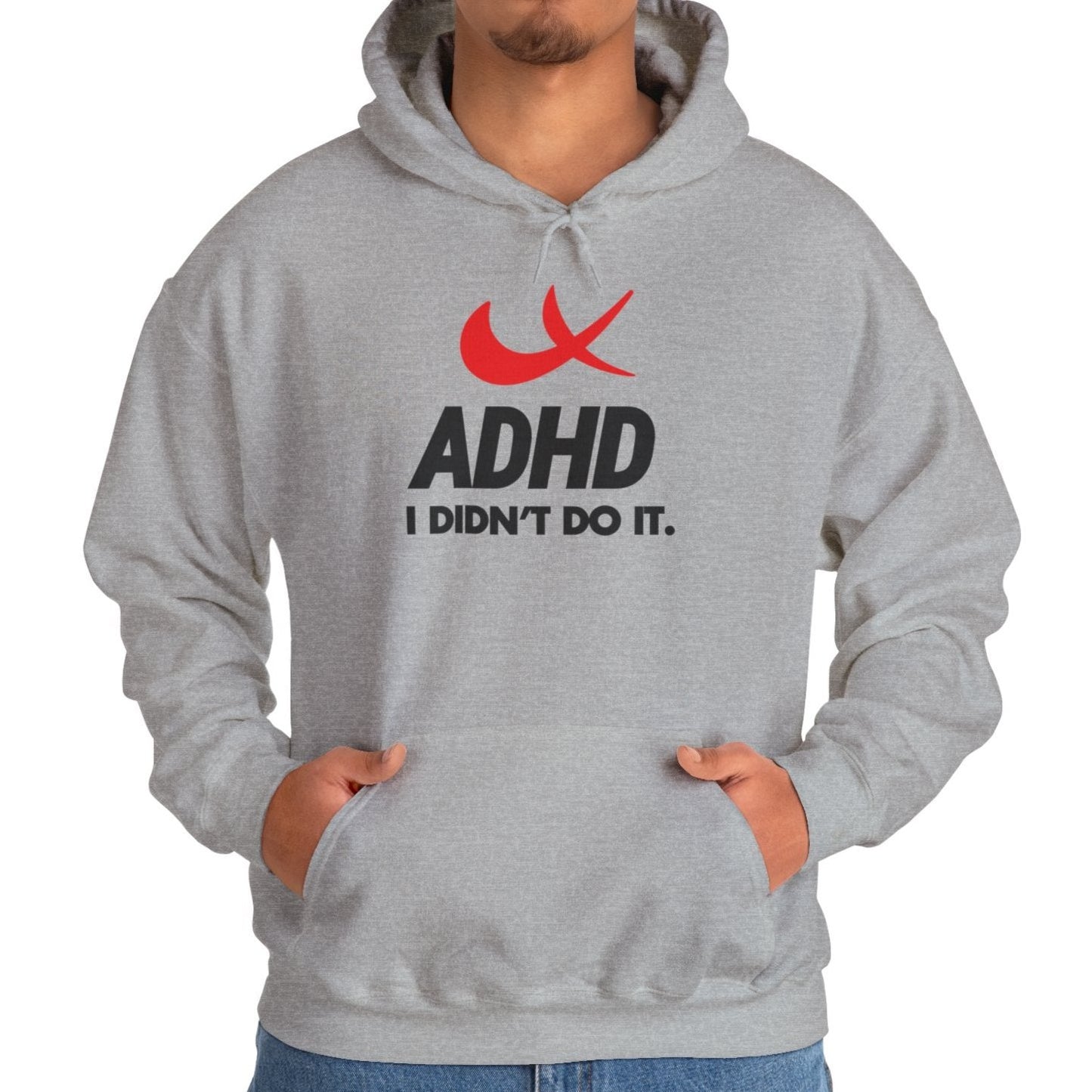 Model wearing a gray hoodie with a Nike parody design featuring a red swoosh and the text "ADHD, I Didn’t Do It." Part of the Vivid Divergence Sensory Friendly Unisex Hoodie Range.