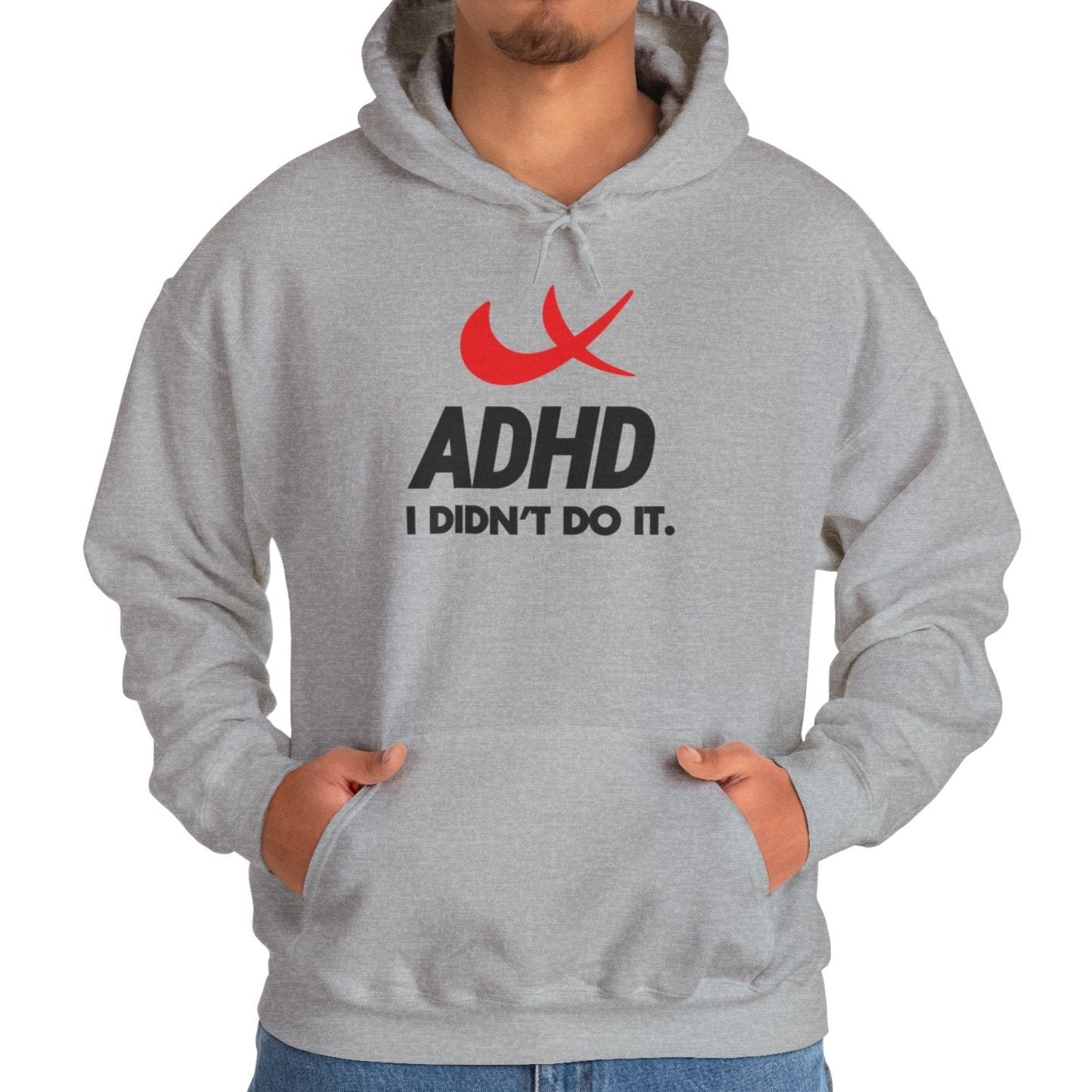 Model wearing a gray hoodie with a Nike parody design featuring a red swoosh and the text "ADHD, I Didn’t Do It." Part of the Vivid Divergence Sensory Friendly Unisex Hoodie Range.