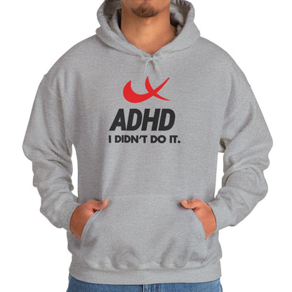Model wearing a gray hoodie with a Nike parody design featuring a red swoosh and the text "ADHD, I Didn’t Do It." Part of the Vivid Divergence Sensory Friendly Unisex Hoodie Range.