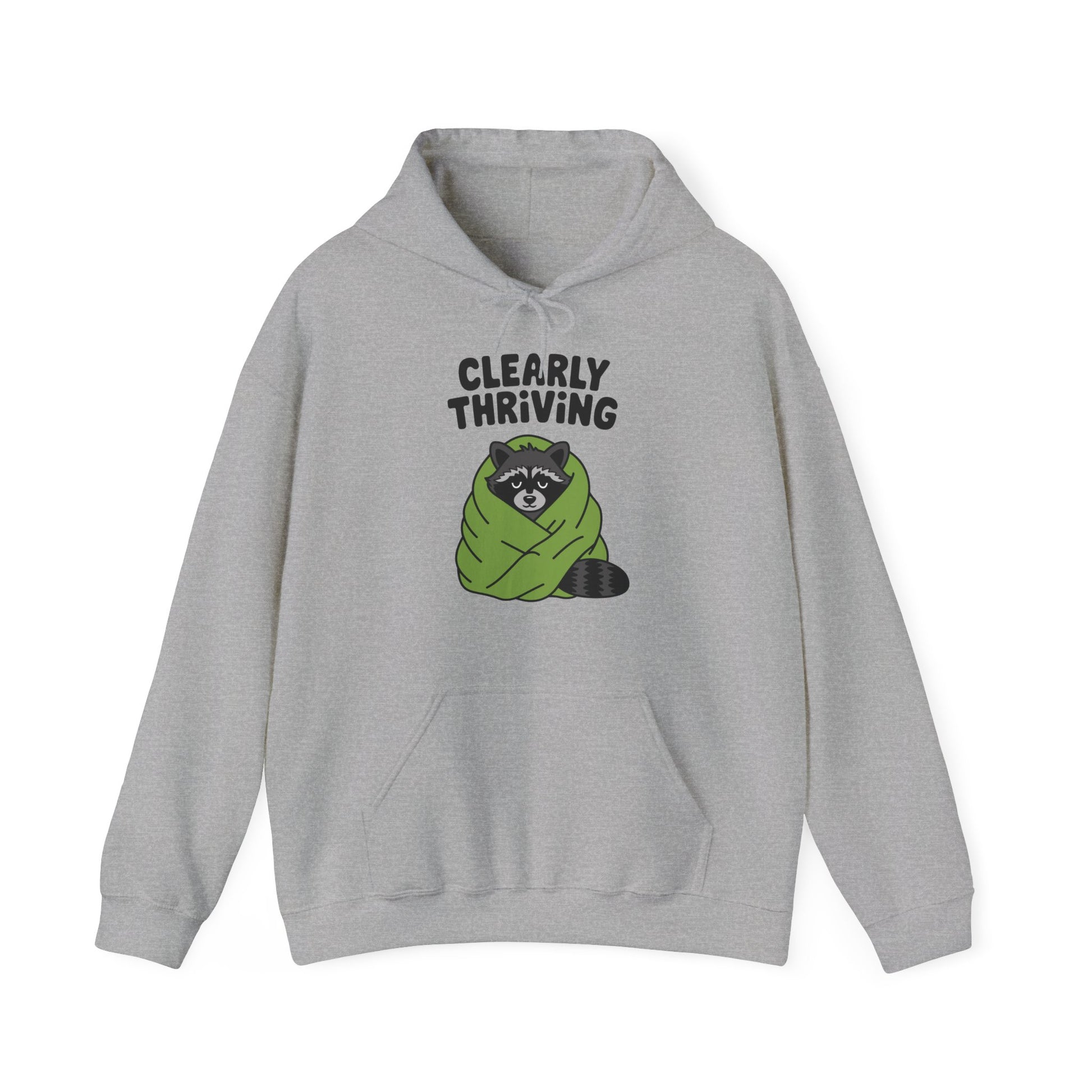Front view of a gray hoodie featuring the text "Clearly Thriving" and a cartoon illustration of a raccoon wrapped in a cozy blanket. Part of the Vivid Divergence Sensory Friendly Unisex Hoodie Range.