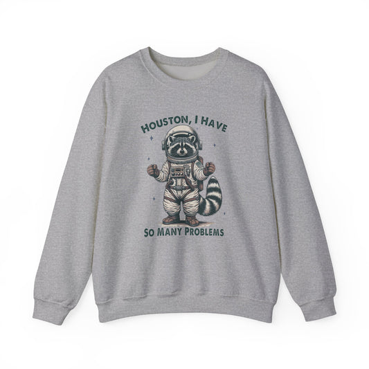 Front view of a gray sweater jumper with the text "Houston, I Have So Many Problems" and a cartoon raccoon illustration holding a striped object. Part of the Vivid Divergence Sensory Friendly Unisex Sweater Jumper Range.