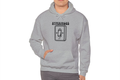 Model wearing a gray hoodie featuring the text "Hyperfocus" and an illustration of a toggle switch turned on. Part of the Vivid Divergence Sensory Friendly Unisex Hoodie Range.