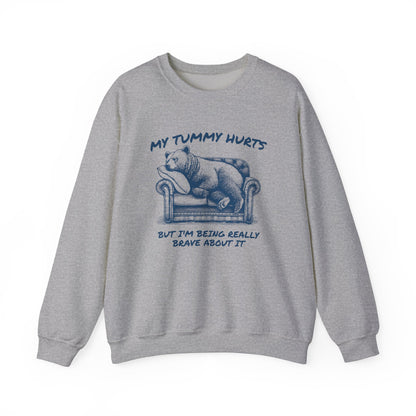Front view of a gray sweater jumper with the text "My Tummy Hurts But I’m Being Really Brave About It" and a cartoon illustration of a bear holding its stomach. Part of the Vivid Divergence Sensory Friendly Unisex Sweater Jumper Range.