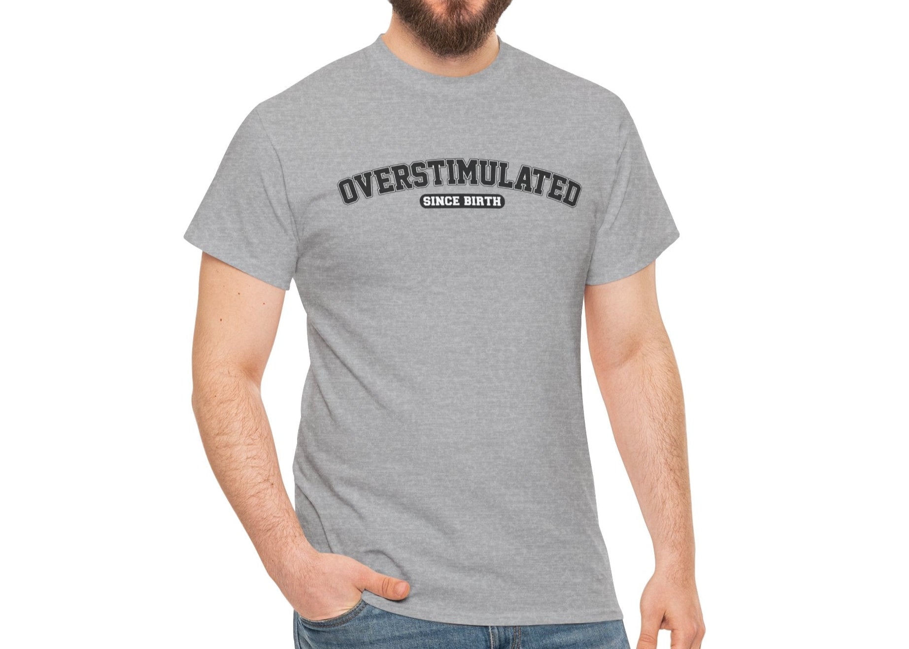 Model wearing a light gray T-shirt with "Overstimulated Since Birth" in bold black text, paired with a yellow beanie. Part of the Vivid Divergence Sensory Friendly Unisex Tees Range.