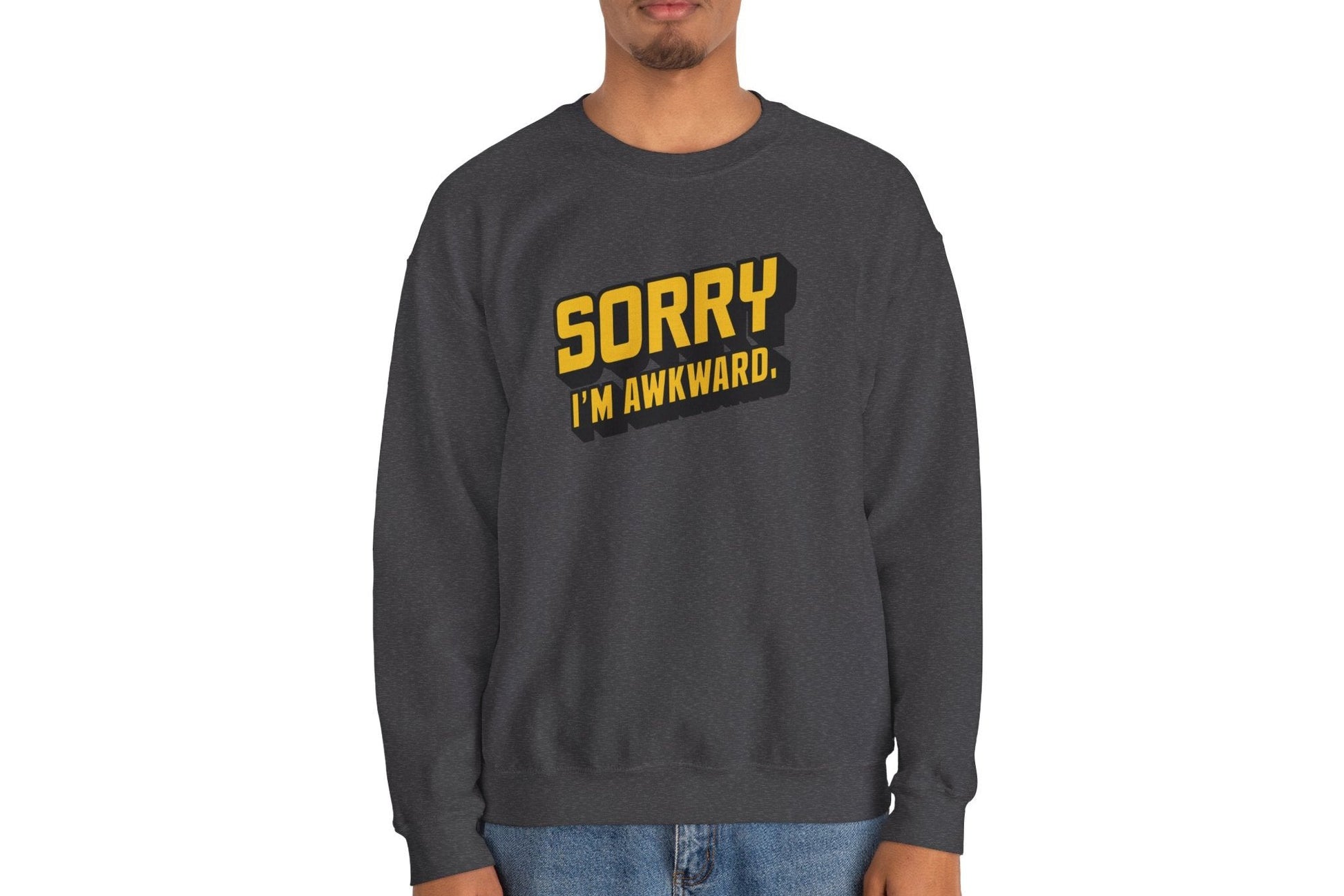 Model wearing a gray sweater jumper with the text "Sorry, I'm Awkward." in bold yellow lettering. Part of the Vivid Divergence Sensory Friendly Unisex Sweater Jumper Range.