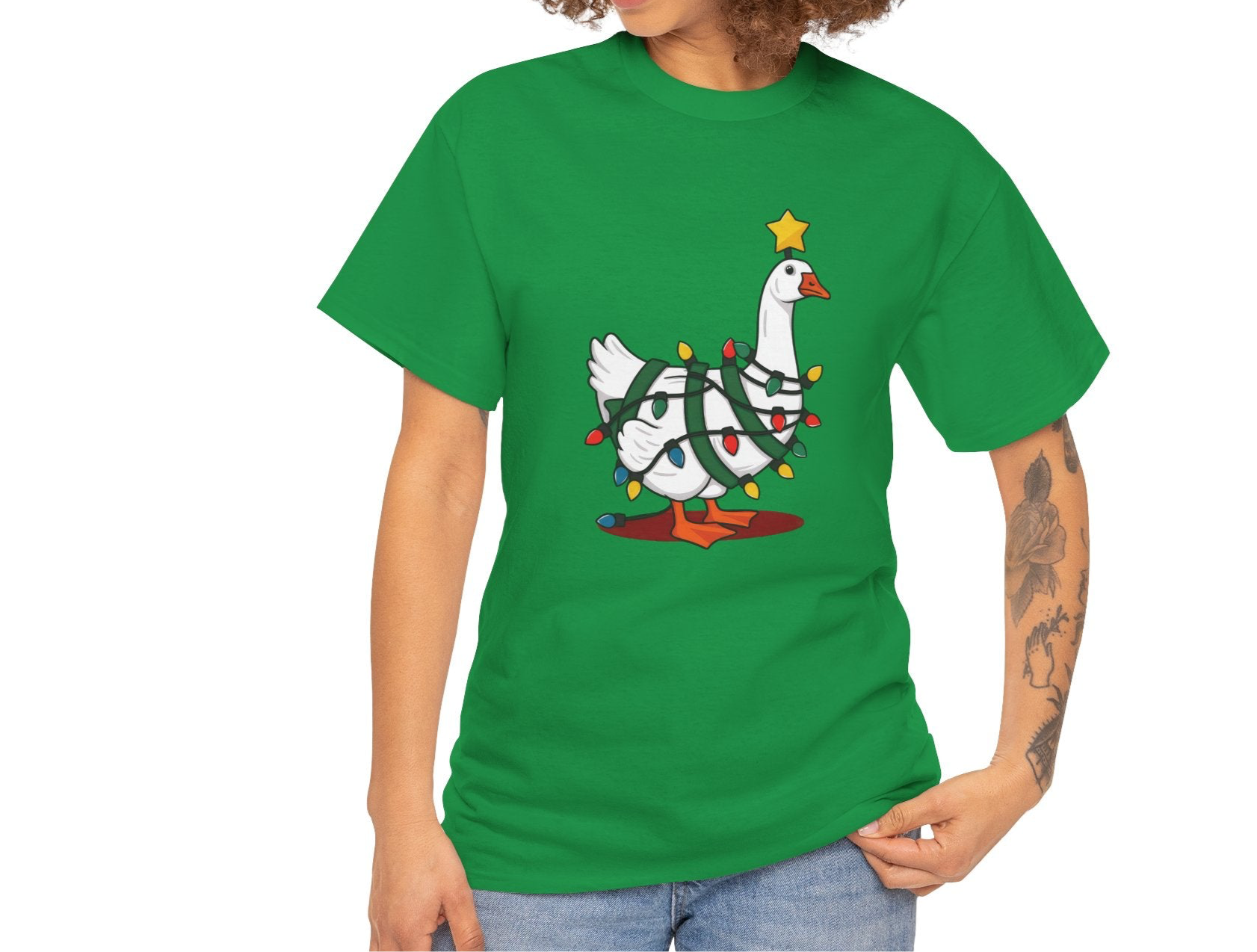 Model wearing a green T-shirt featuring a festive illustration of a goose wearing a Santa hat and stringing Christmas lights, with the text "Goose on the Loose." Part of the Vivid Divergence Sensory Friendly Unisex Tees Range.