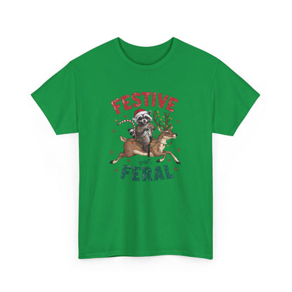 Front view of a green T-shirt featuring a festive illustration of a raccoon (trash panda) holding Christmas lights and the text "Festive but Feral." Part of the Vivid Divergence Sensory Friendly Unisex Tees Range.