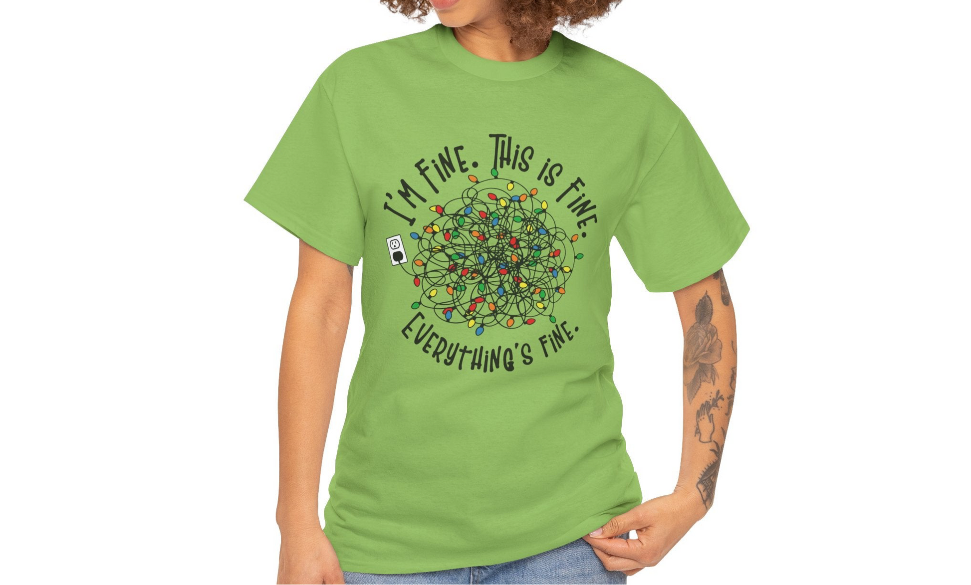 Model wearing a green T-shirt with a festive tangled Christmas lights design and the phrase "I'm Fine. This is Fine. Everything's Fine." Part of the Vivid Divergence Sensory Friendly Unisex Tees Range