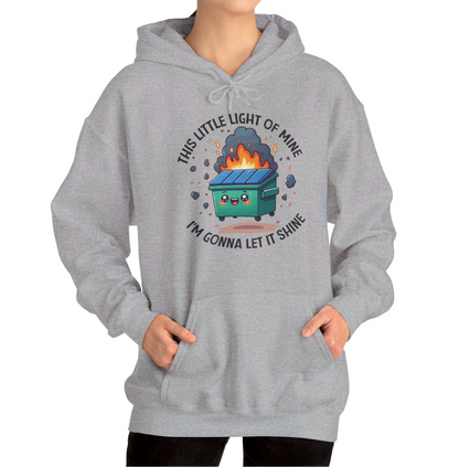 Model wearing a grey hoodie featuring the text "This Little Light of Mine, I'm Gonna Let It Shine" and a cartoon illustration of a dumpster fire with glowing flames. Part of the Vivid Divergence Sensory Friendly Unisex Hoodie Range.
