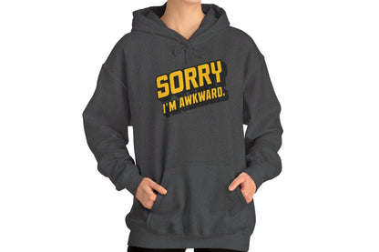 Model wearing a grey hoodie featuring the text "Sorry I'm Awkward" in bold yellow and white lettering. Part of the Vivid Divergence Sensory Friendly Unisex Hoodie Range.