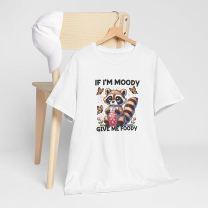 Front hanging view of a white T-shirt featuring a raccoon graphic with food and the text "If I'm Moody, Give Me Foody." Part of the Vivid Divergence Sensory Friendly Unisex Tees Range.