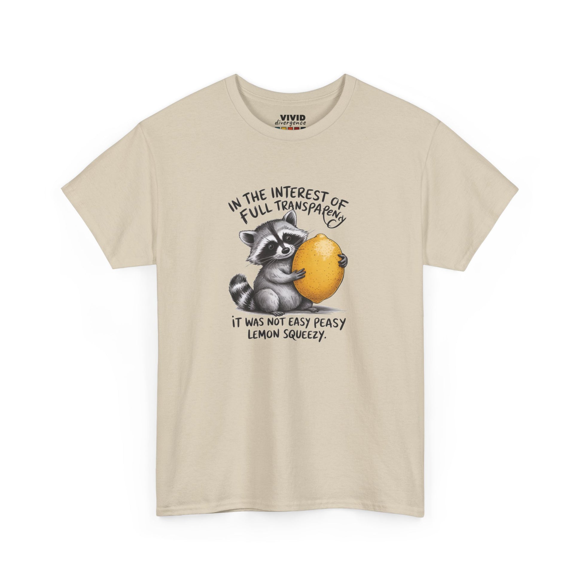 Front view of beige T-shirt featuring a raccoon holding onto a lemon with the text “In the interest of transparency, it was not easy peasy lemon squeezy.” The emotional squeeze is real. Part of the Vivid Divergence Memewear Collection!