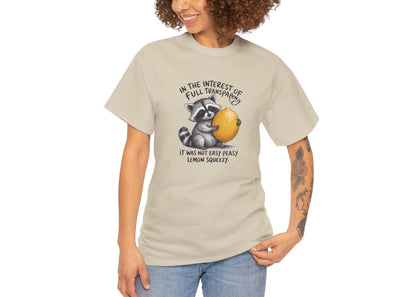 Modeled view of beige T-shirt featuring a raccoon holding onto a lemon with the text “In the interest of transparency, it was not easy peasy lemon squeezy.” The emotional squeeze is real. Part of the Vivid Divergence Memewear Collection!