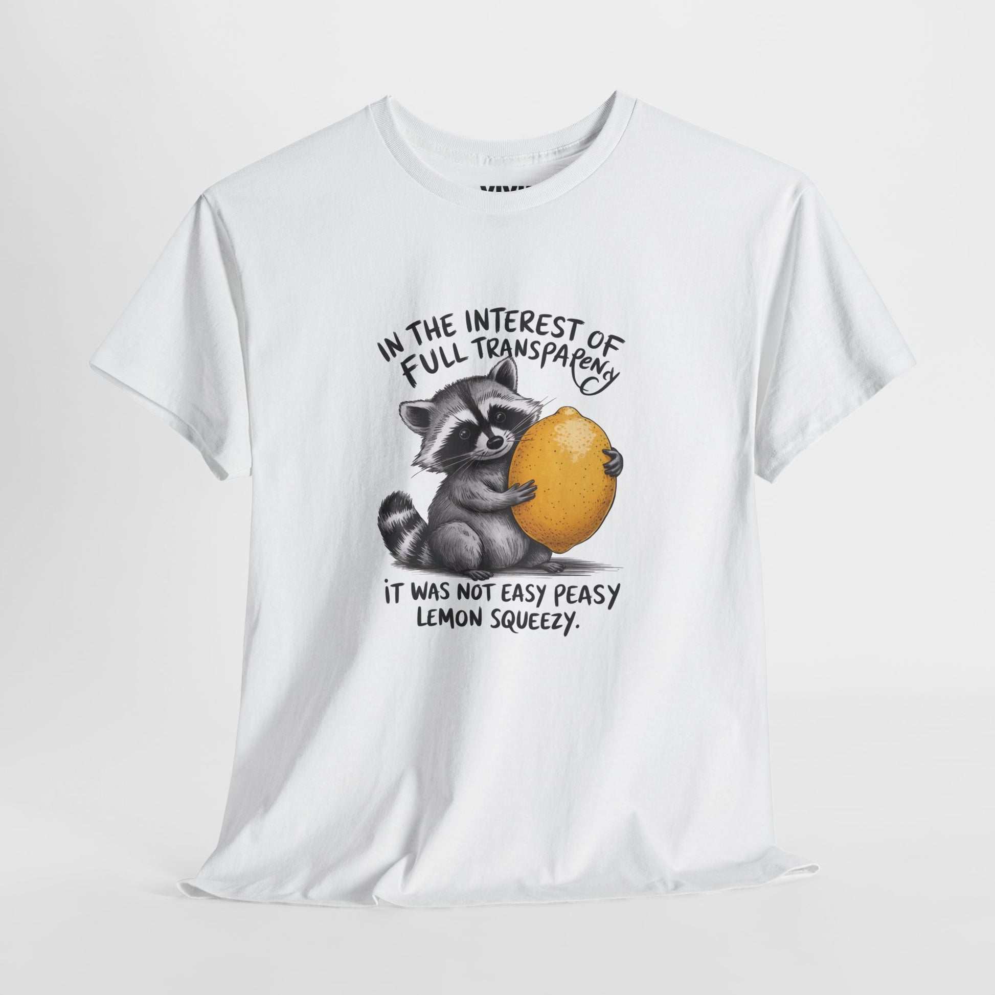 Hanging view of white T-shirt featuring a raccoon holding onto a lemon with the text “In the interest of transparency, it was not easy peasy lemon squeezy.” The emotional squeeze is real. Part of the Vivid Divergence Memewear Collection!
