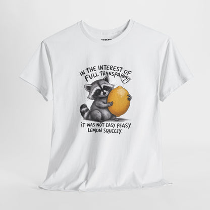 Hanging view of white T-shirt featuring a raccoon holding onto a lemon with the text “In the interest of transparency, it was not easy peasy lemon squeezy.” The emotional squeeze is real. Part of the Vivid Divergence Memewear Collection!