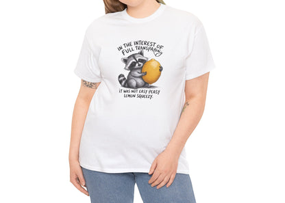 Modeled view of white T-shirt featuring a raccoon holding onto a lemon with the text “In the interest of transparency, it was not easy peasy lemon squeezy.” The emotional squeeze is real. Part of the Vivid Divergence Memewear Collection!