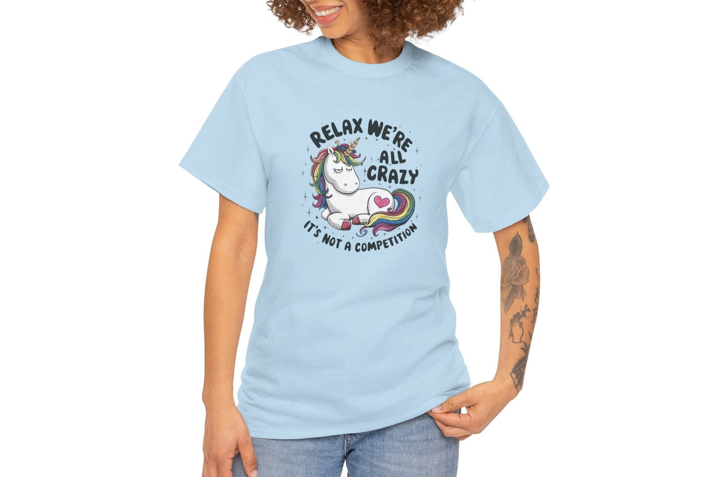 Model wearing a light blue T-shirt with "Relax, We're All Crazy" and a whimsical cat graphic in black text. Part of the Vivid Divergence Sensory Friendly Unisex Tees Range.