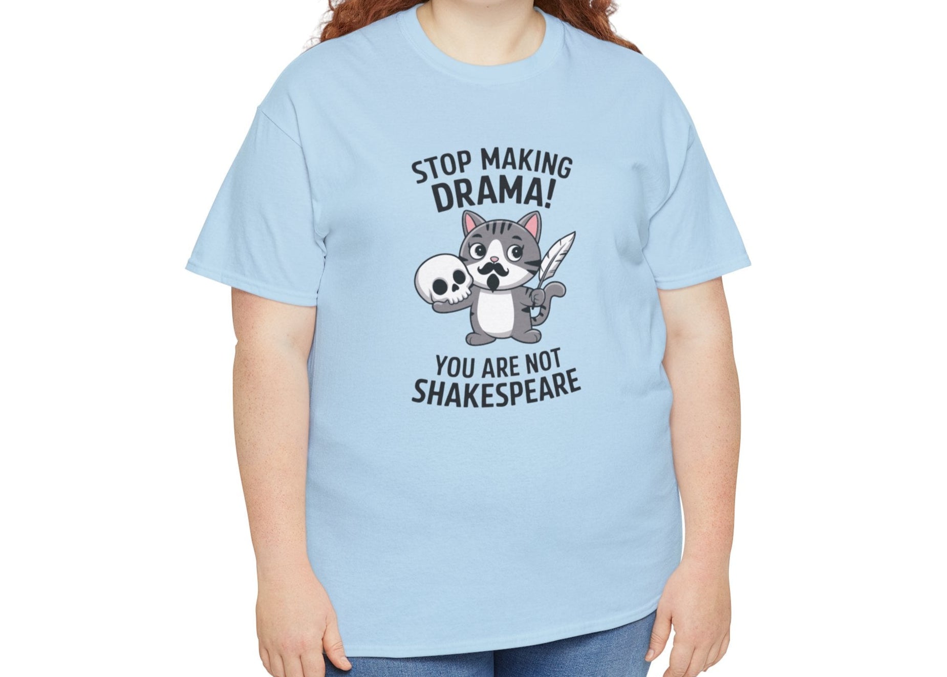 Modeled front view of a light blue T-shirt featuring a cute cat holding a skull and text that reads "Stop Making Drama! You Are Not Shakespeare." Part of the Vivid Divergence Sensory Friendly Unisex Tees Range.