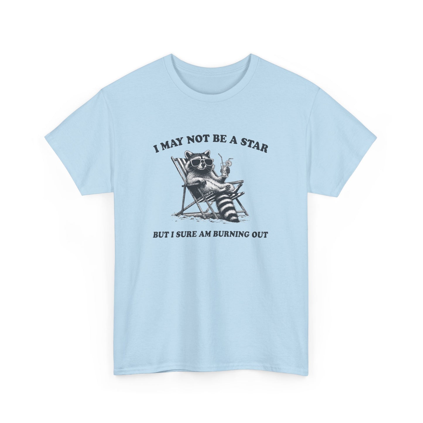 Hanging front view of a light blue T-shirt featuring a cute raccoon holding a star with text that reads "I May Not Be A Star, But I Sure Am Burning Out." Part of the Vivid Divergence Sensory Friendly Unisex Tees Range.