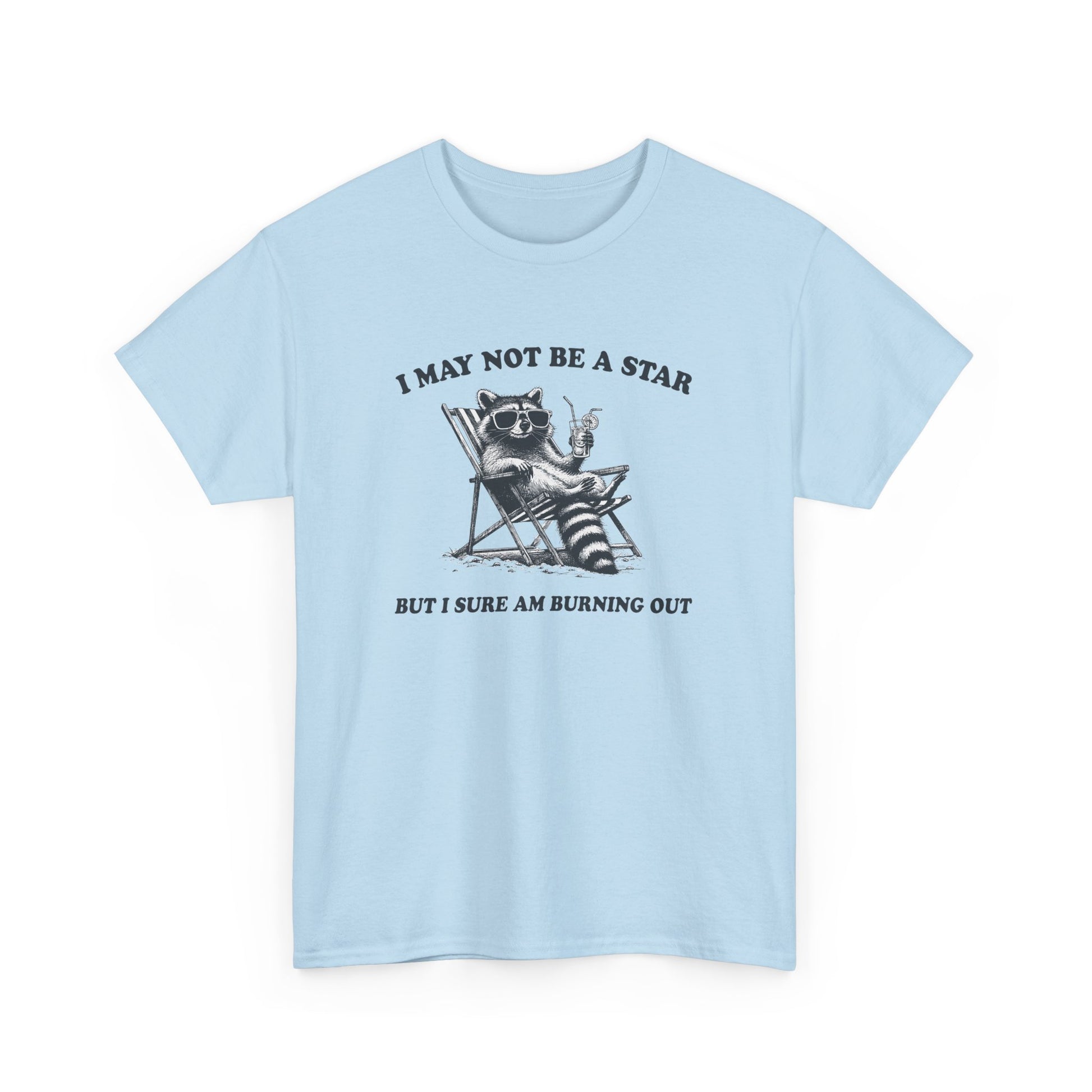 Hanging front view of a light blue T-shirt featuring a cute raccoon holding a star with text that reads "I May Not Be A Star, But I Sure Am Burning Out." Part of the Vivid Divergence Sensory Friendly Unisex Tees Range.