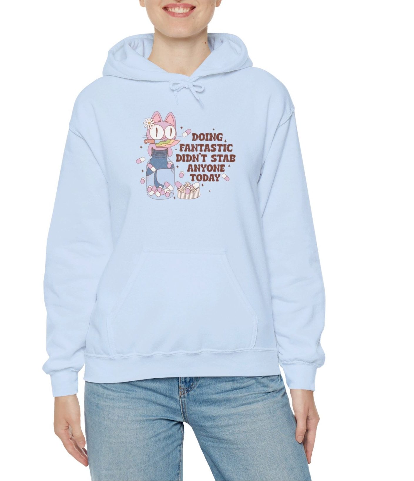 Model wearing a light blue hoodie featuring the text "Doing Fantastic, Didn’t Stab Anyone Today" and a cartoon illustration of a raccoon holding a knife. Part of the Vivid Divergence Sensory Friendly Unisex Hoodie Range.