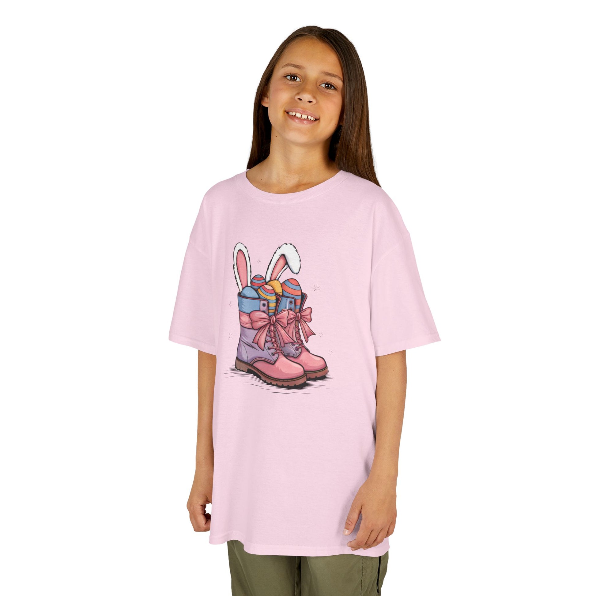 Child wearing a pink Easter T-shirt with cowgirl boots, Easter eggs, and bunny ears. A playful and festive holiday outfit. Hop into the season in style and shop Easter shirts online today!
