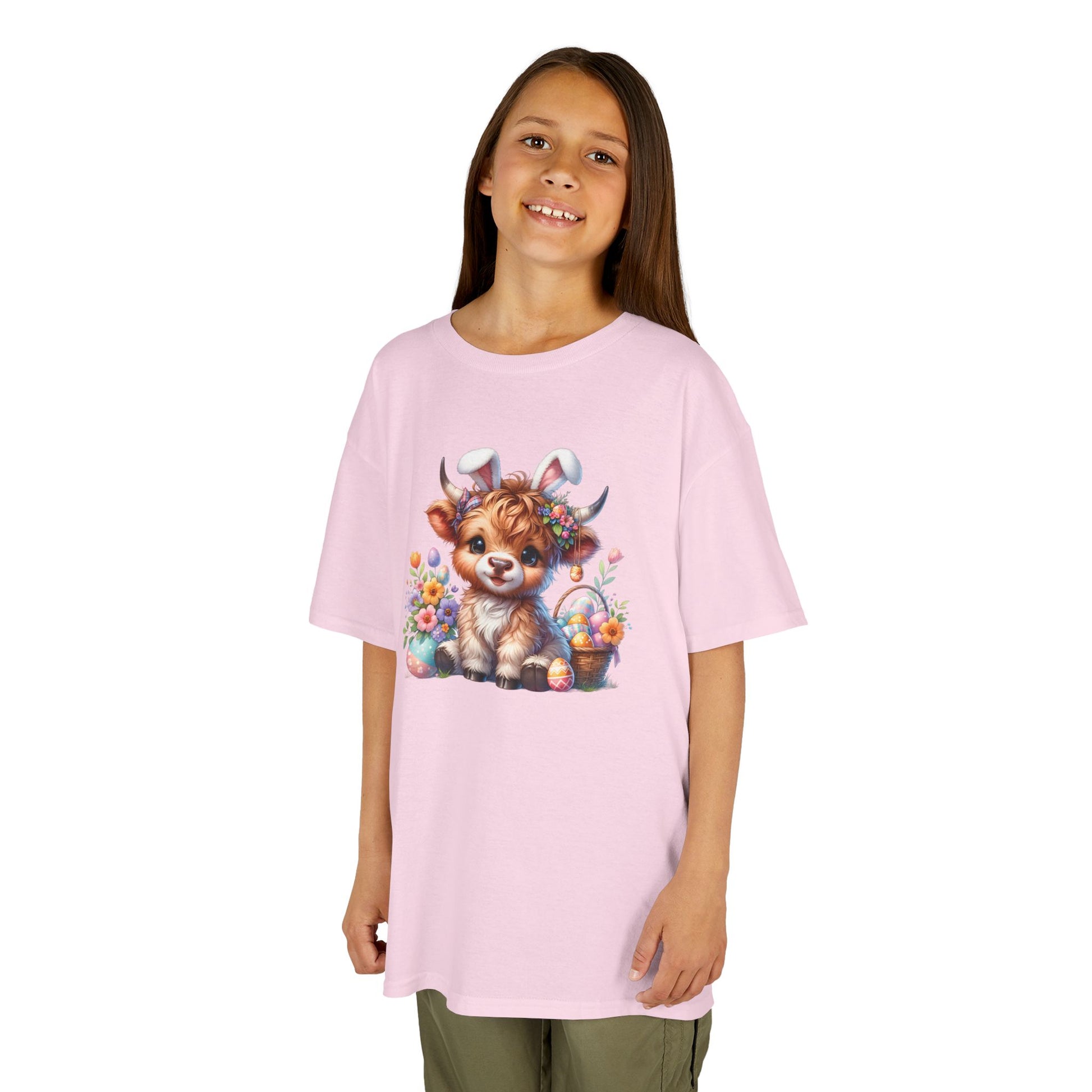 Child wearing a pink Easter T-shirt with a Highland cow, pastel-colored eggs, and flowers, a soft and stylish outfit. Hop into the season in style and shop Easter shirts online today!