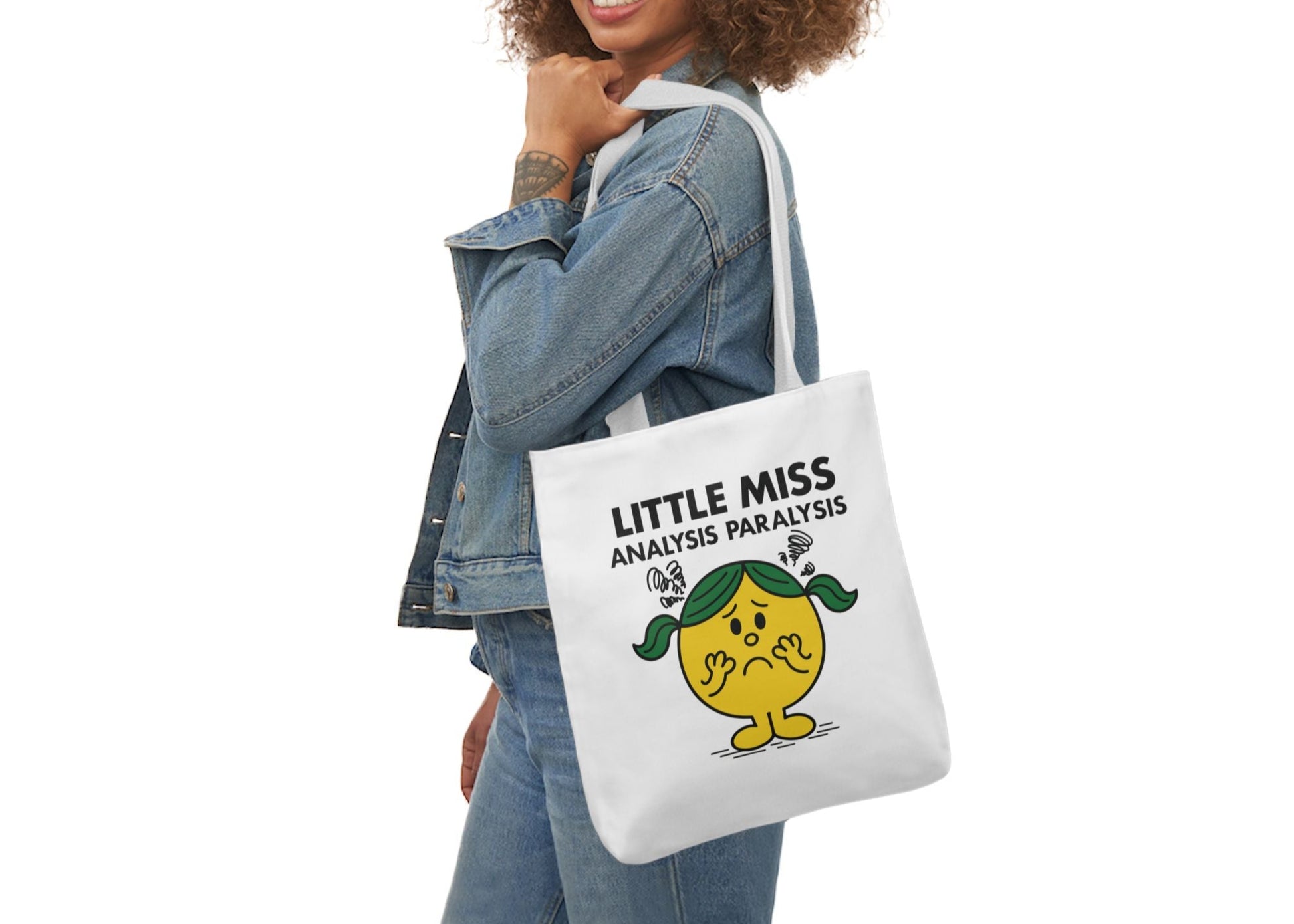 Woman in denim outfit wearing the Little Miss Analysis Paralysis tote bag on her shoulder, still pondering her outfit choice. Part of the Vivid Divergence Little Miss Meme Collection!
