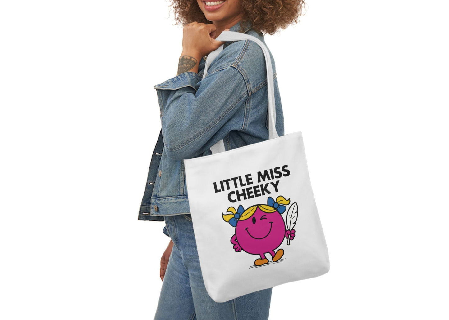 Woman in denim smiling while modeling the Little Miss Cheeky tote over her shoulder — that grin says “zero regrets.” Part of the Vivid Divergence Little Miss Meme Collection!
