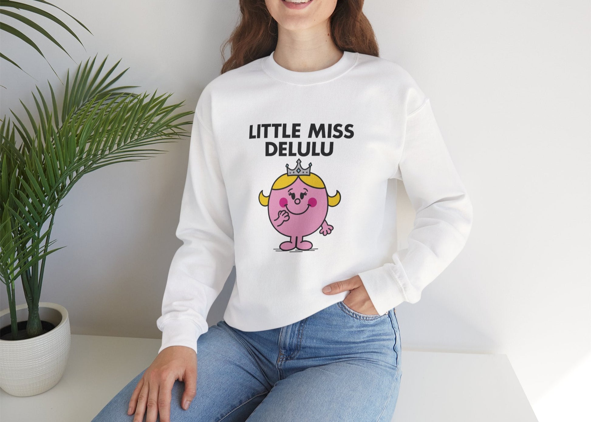 Person wearing the Little Miss Delulu sweatshirt while seated casually. Part of the Little Miss Meme Character Collection. A Vivid Divergence Sensory Friendly Sweater Jumper.
