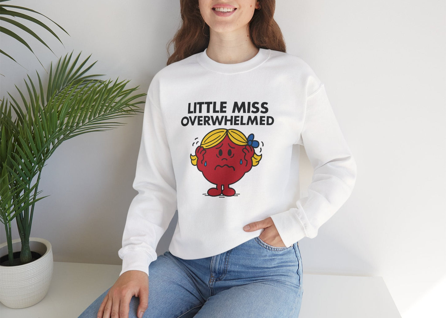Person wearing the Little Miss Overwhelmed sweatshirt while seated in a casual pose. Part of the Little Miss Meme Character Collection. A Vivid Divergence Sensory Friendly Sweater Jumper.
