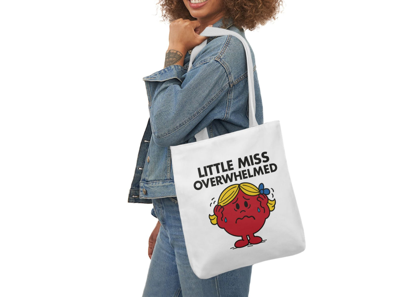 Woman in denim modeling the Little Miss Overwhelmed tote over her shoulder. She's smiling through the chaos. Barely. Part of the Vivid Divergence Little Miss Meme Collection!
