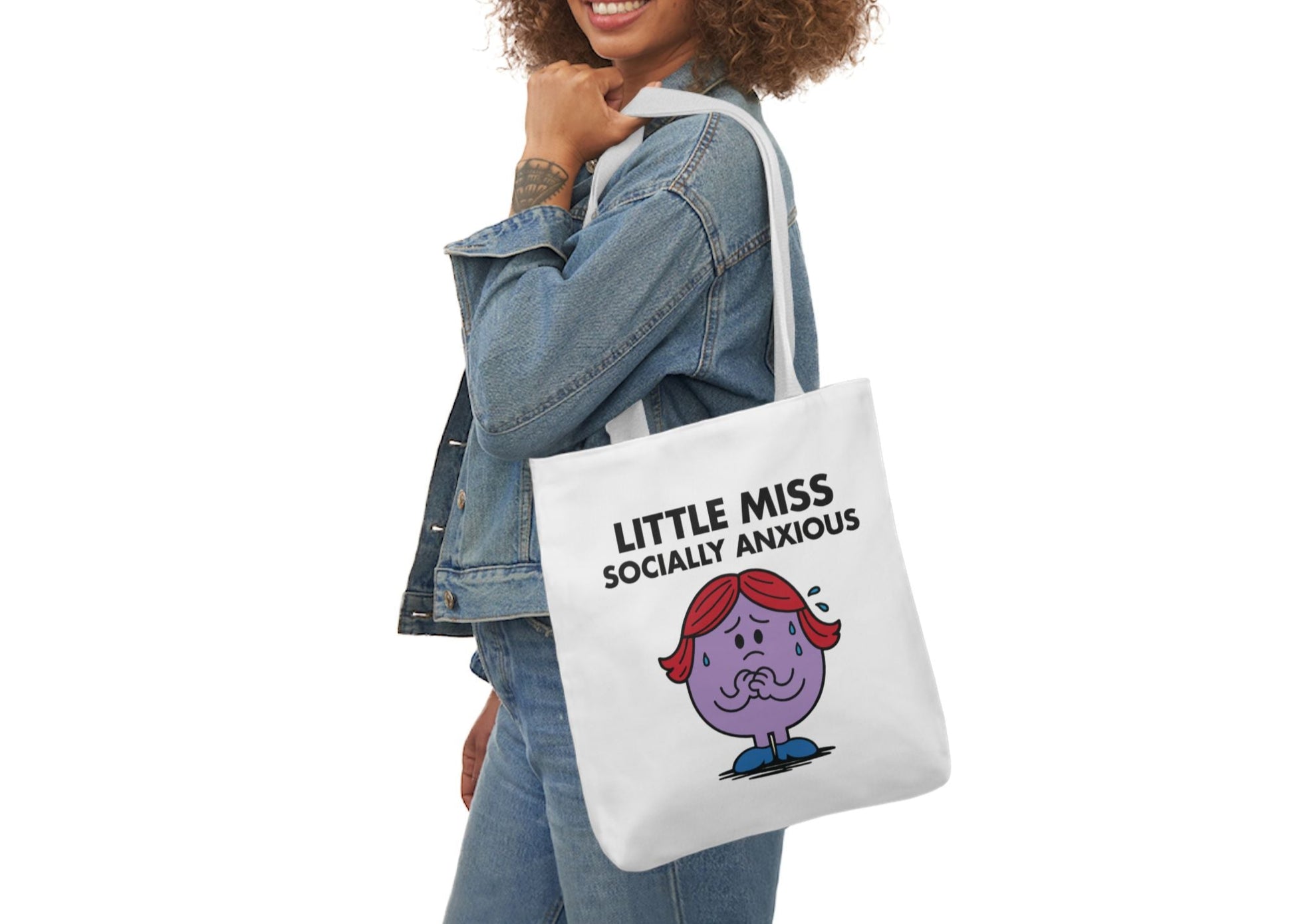 Woman in denim modeling the Little Miss Socially Anxious tote bag over her shoulder. She smiled, but she’s already planning her exit. Part of the Vivid Divergence Little Miss Meme Collection!
