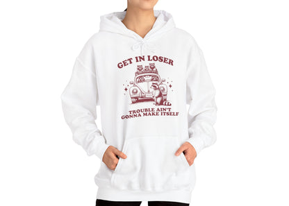 Model wearing a white hoodie with "Get in Loser, Trouble Ain't Gonna Make Itself" in red letters and a group of raccoons riding in a car, adjusting the hood. Part of the Vivid Divergence Sensory Friendly Unisex Hoodie Range.