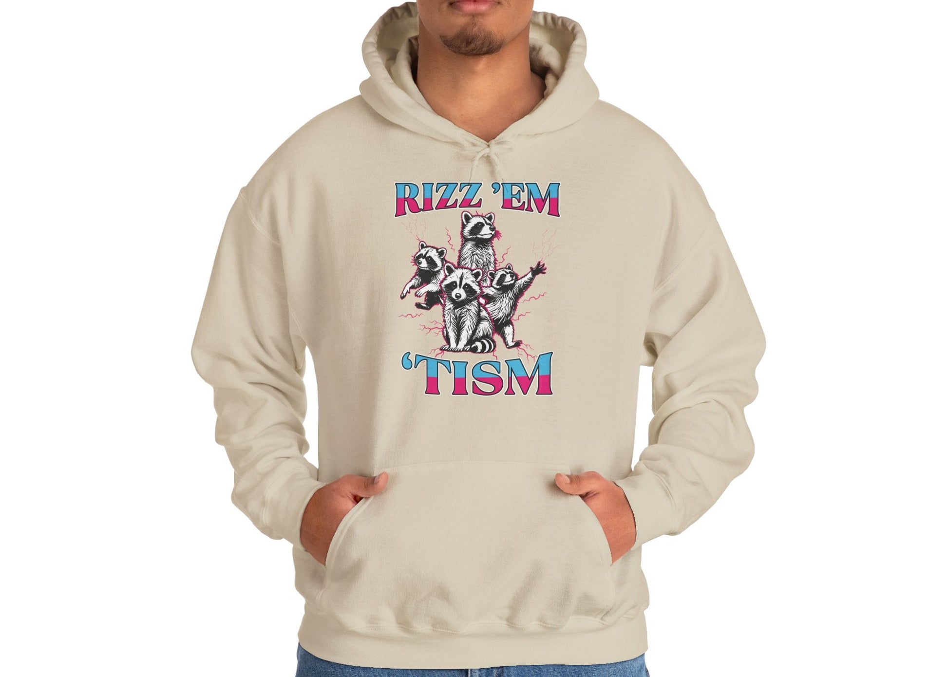 Model wearing a beige hoodie with a raccoon illustration and the text "Rizz 'Em 'Tism," standing with hands in pockets. Part of the Vivid Divergence Sensory Friendly Unisex Hoodie Range.