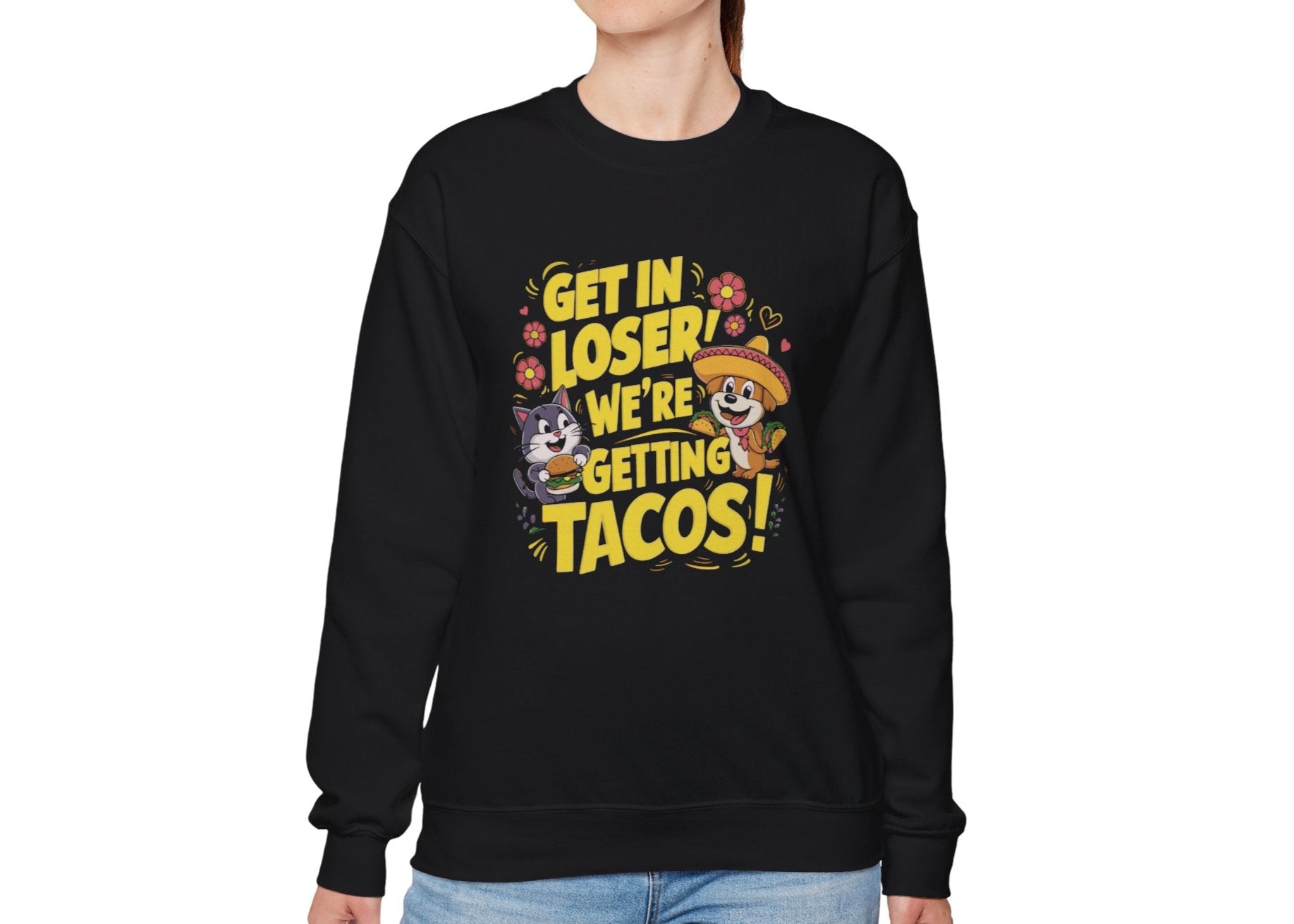 Model wearing a black sweatshirt with colorful cartoon animals and the text "Get in Loser, We're Getting Tacos!" standing with hands at sides. Part of the Vivid Divergence Sensory Friendly Unisex Sweater Jumper Range.