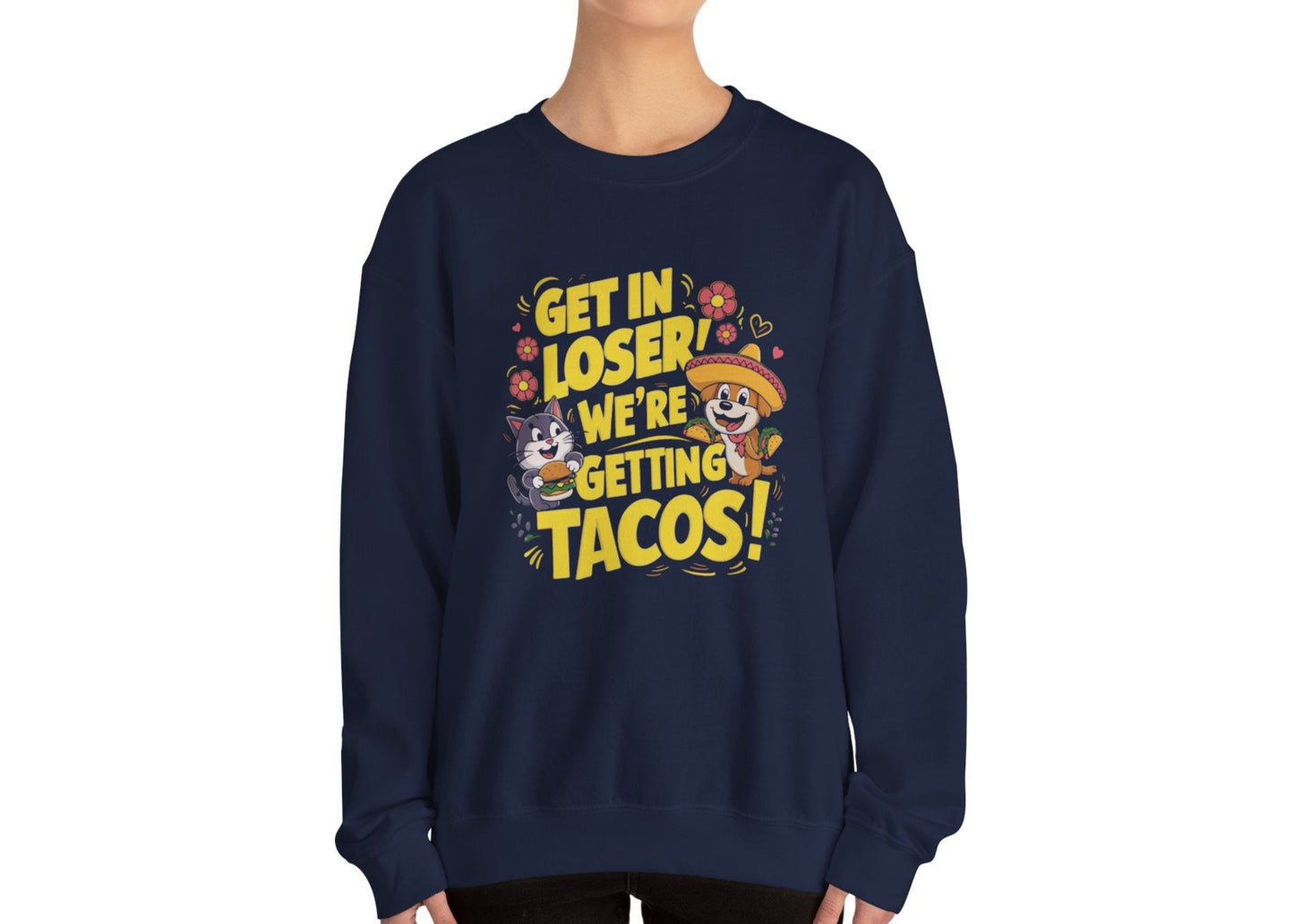 Model wearing a navy blue sweatshirt with colorful cartoon animals and the text "Get in Loser, We're Getting Tacos!" standing with hands at sides. Part of the Vivid Divergence Sensory Friendly Unisex Sweater Jumper Range.