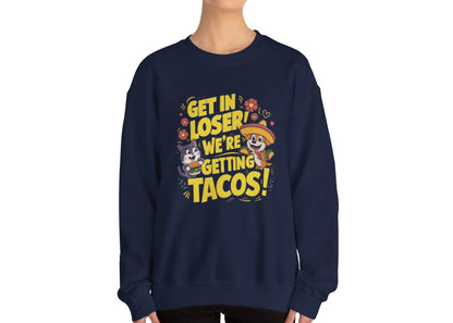Model wearing a navy blue sweatshirt with colorful cartoon animals and the text "Get in Loser, We're Getting Tacos!" standing with hands at sides. Part of the Vivid Divergence Sensory Friendly Unisex Sweater Jumper Range.