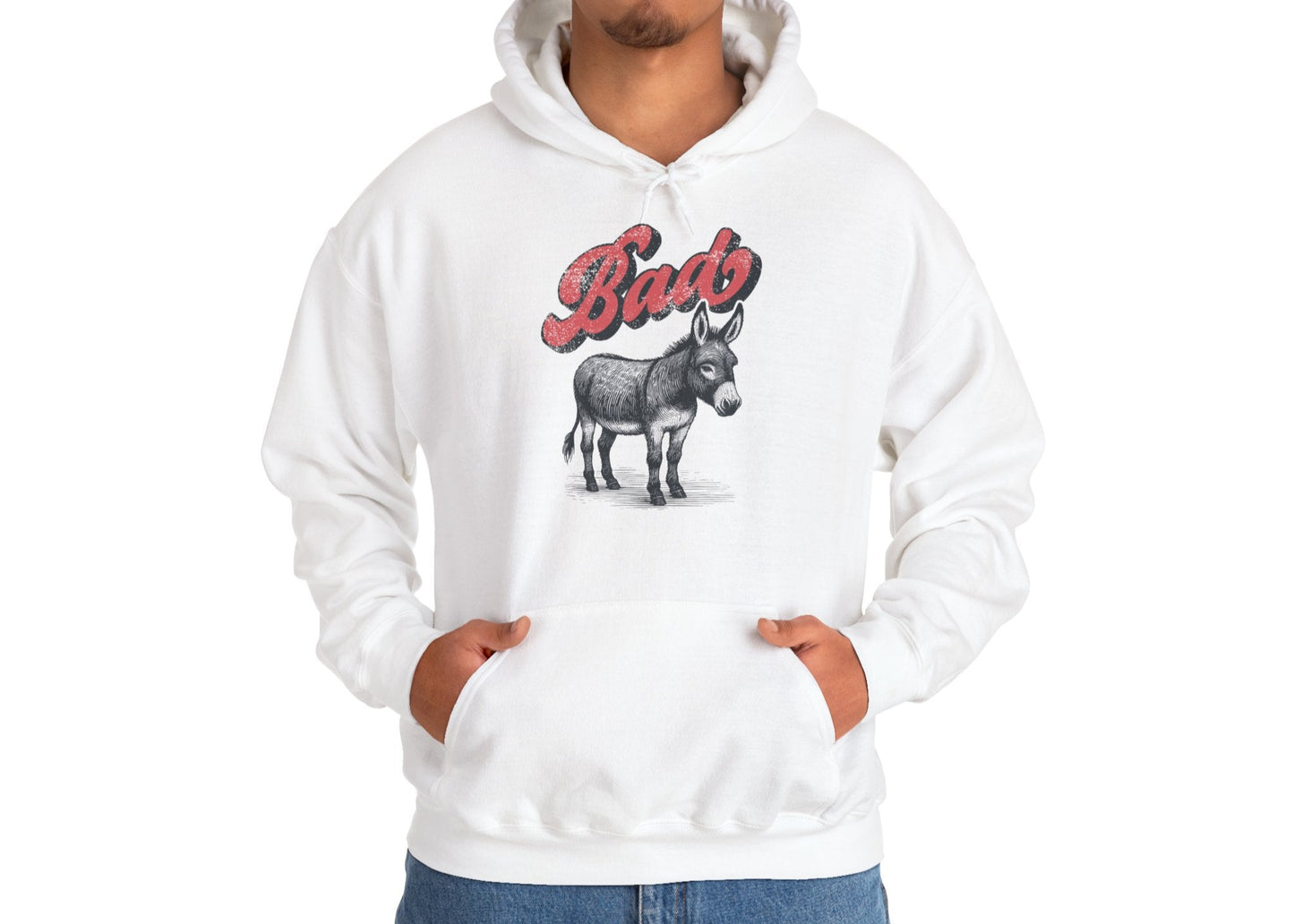 Model wearing a white hoodie with the word "Bad" in bold red letters and a donkey illustration, standing with hands in pockets. Part of the Vivid Divergence Sensory Friendly Unisex Hoodie Range.