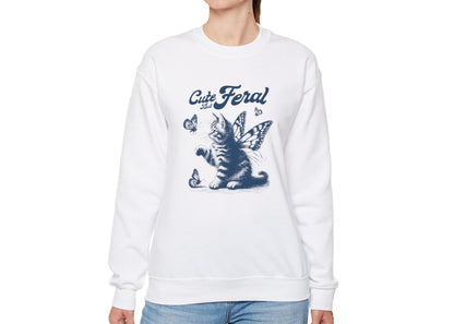 Model wearing a white sweatshirt with a graphic of a cat surrounded by butterflies and the text "Cat Feral," standing with hands at sides. Part of the Vivid Divergence Sensory Friendly Unisex Sweater Jumper Range.