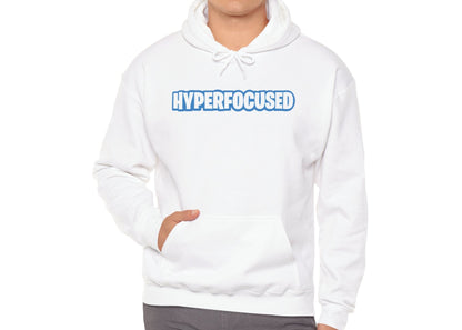 Model wearing a white hoodie with the word "HYPERFOCUSED" in a bold, blue Fortnite-style font, standing with hands in pockets. Part of the Vivid Divergence Sensory Friendly Unisex Hoodie Range.