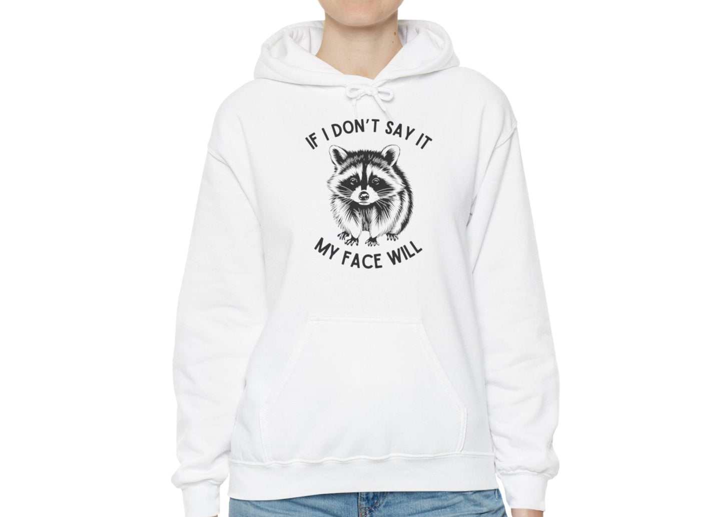 Model wearing a white hoodie with a raccoon graphic and the text "If I Don't Say It, My Face Will," standing with hands at sides. Part of the Vivid Divergence Sensory Friendly Unisex Hoodie Range.