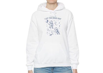 Model wearing a white hoodie with playful dog illustrations and the text "It Was Me, I Let The Dogs Out," standing with hands at sides. Part of the Vivid Divergence Sensory Friendly Unisex Hoodie Range.