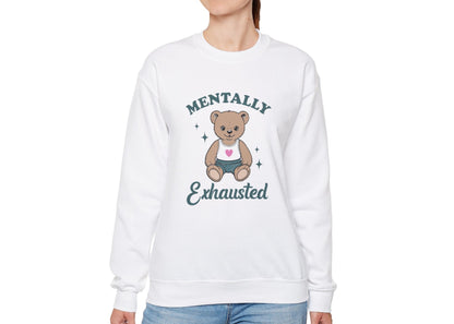 Model wearing a white sweatshirt with a cute teddy bear wearing an apron and the text "Mentally Exhausted," standing with hands at sides. Part of the Vivid Divergence Sensory Friendly Unisex Sweater Jumper Range.