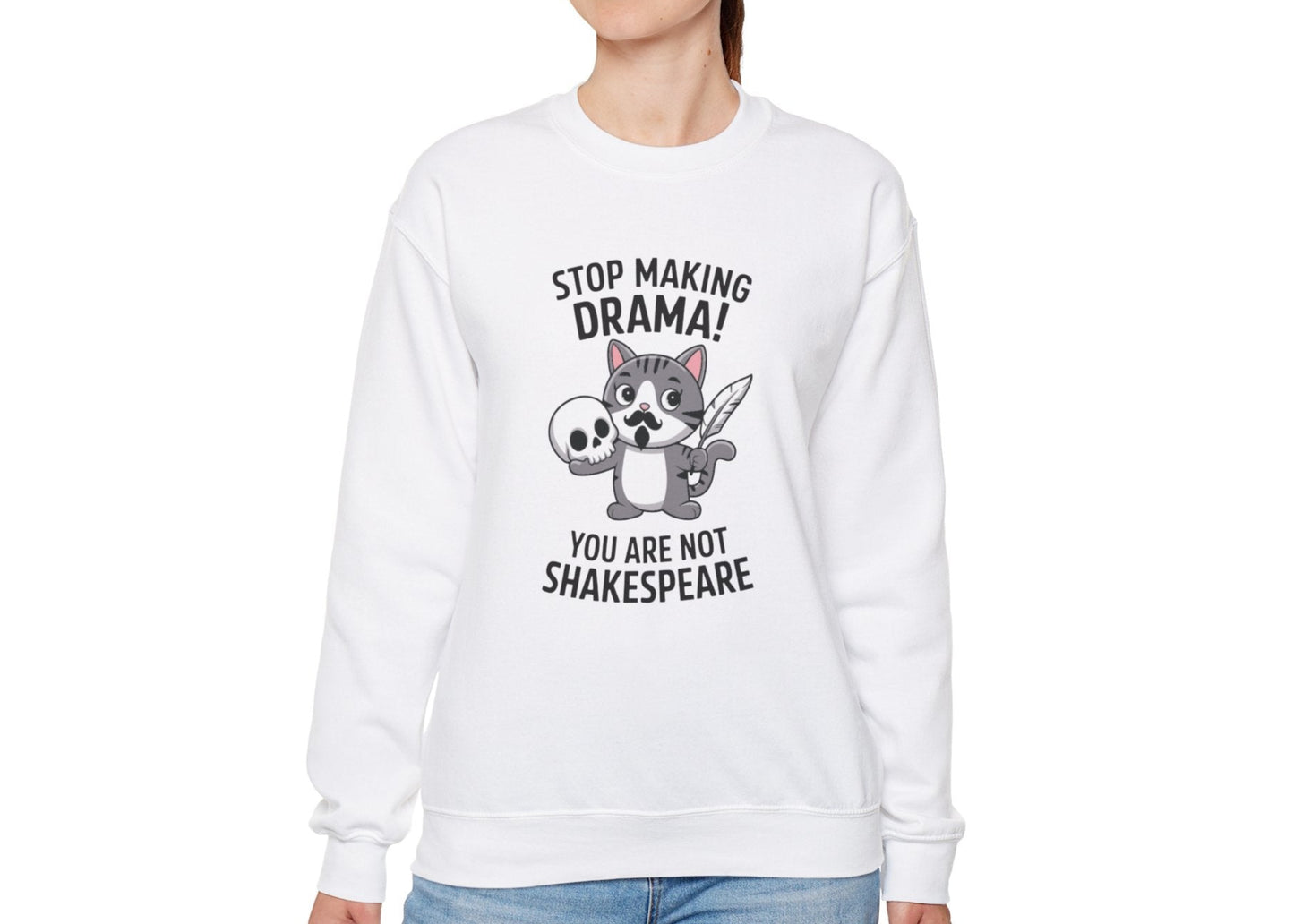 Model wearing a white sweatshirt with a cartoon cat holding a skull and the text "Stop Making Drama! You Are Not Shakespeare," standing with hands at sides. Part of the Vivid Divergence Sensory Friendly Unisex Sweater Jumper Range.