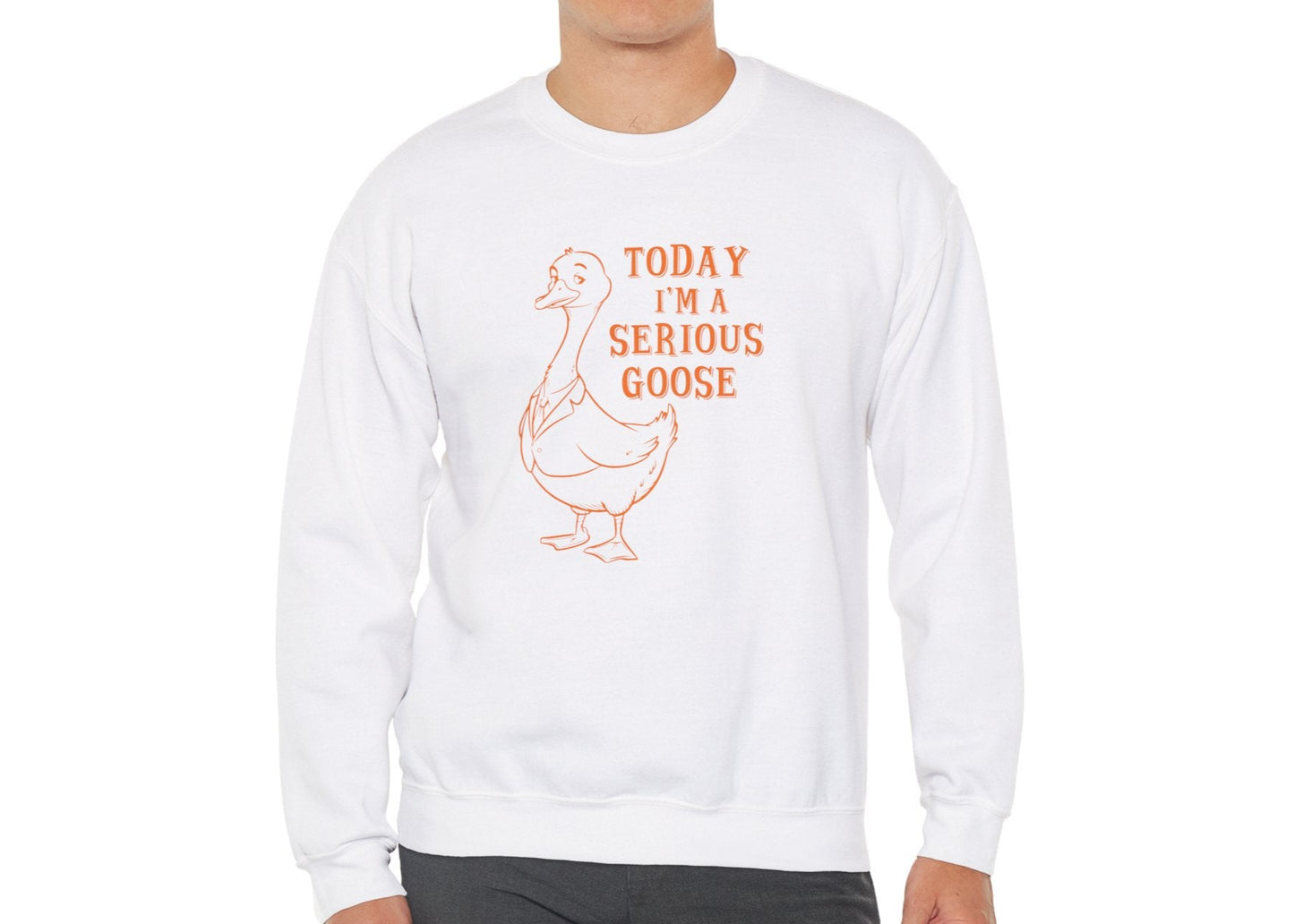 Model wearing a white sweatshirt with "Today I'm a Serious Goose" in orange letters and a cartoon goose, standing with hands at sides. Part of the Vivid Divergence Sensory Friendly Unisex Sweater Jumper Range.